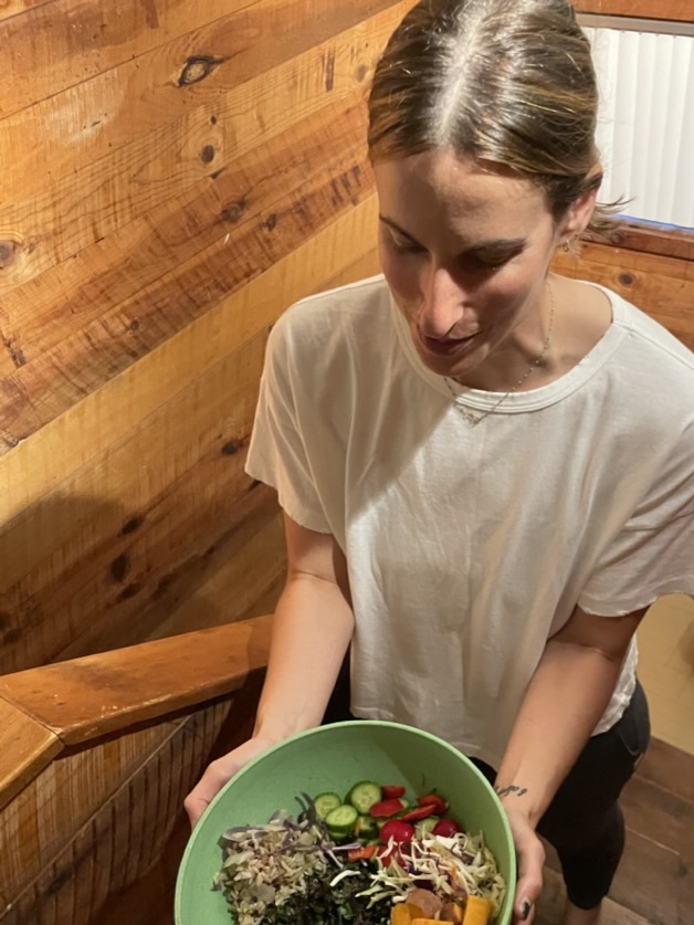 Deborah Tenenbaum, NP, holding a big bowl of salad with greens, squash, and vegetables.